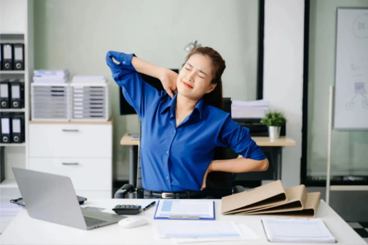 Woman stretching her arms behind her head at an office desk