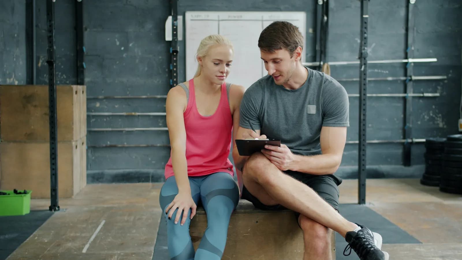Coach and client reviewing a training plan on a tablet in the gym