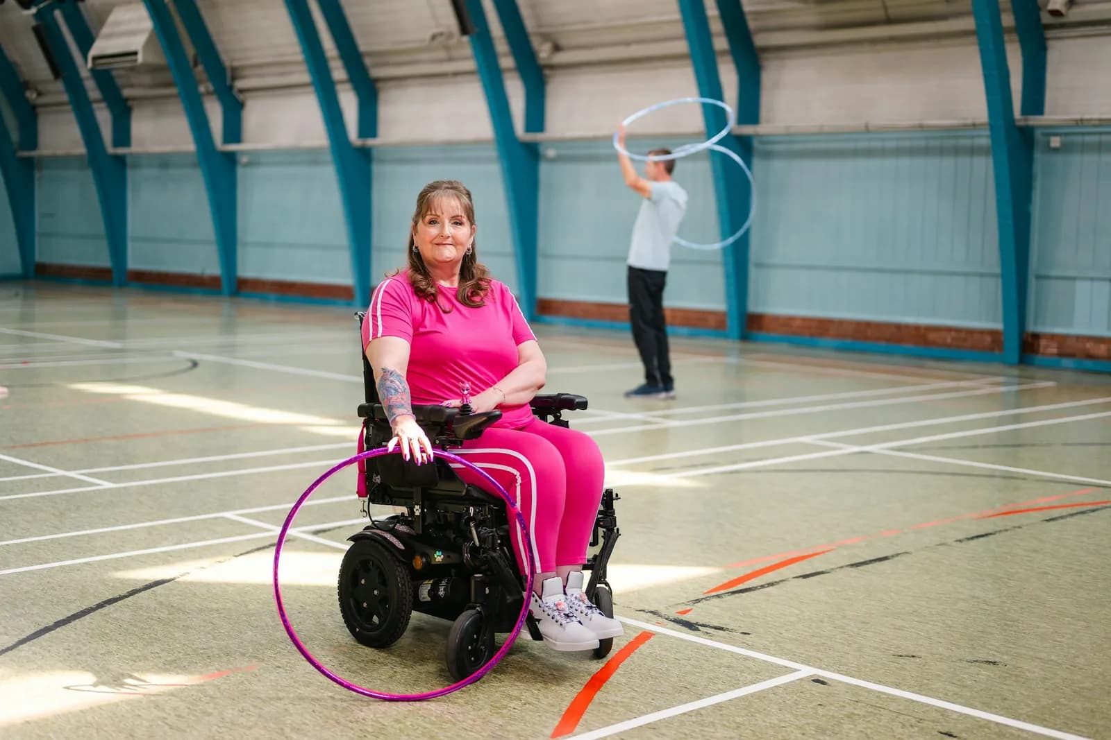 Woman in a wheelchair exercising with a hula hoop in a sports hall