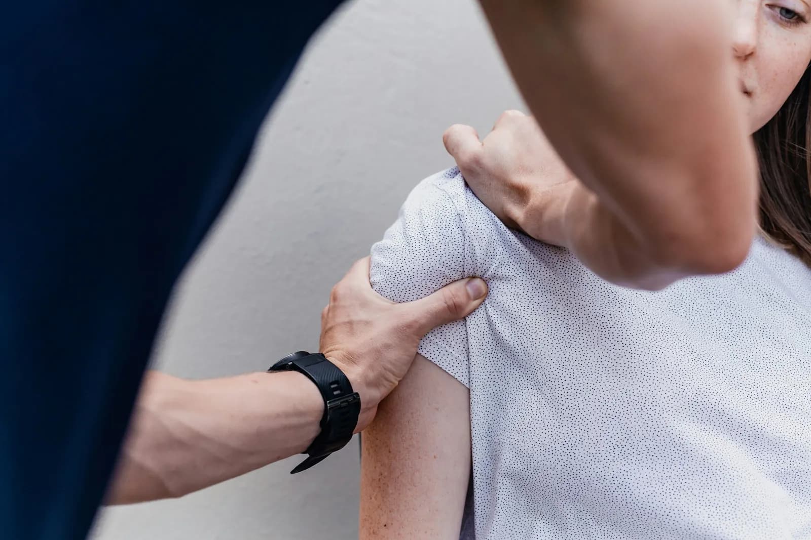 Clinician's hands supporting a patient's shoulder during treatment