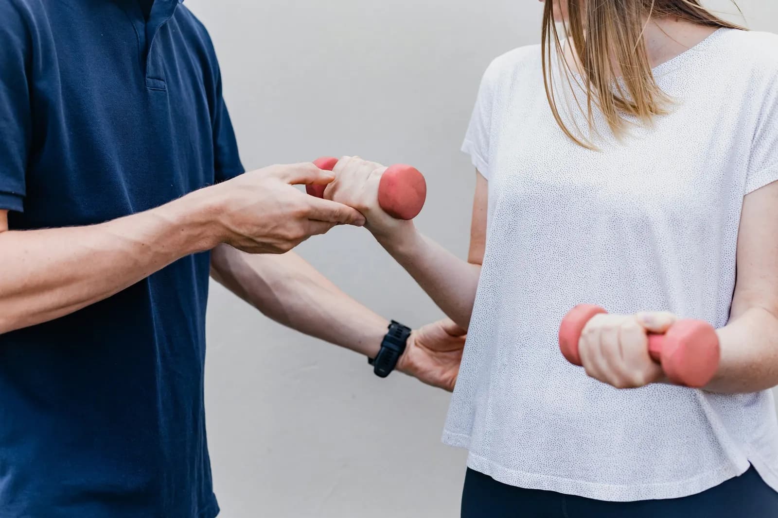 Clinician guiding a patient through a light dumbbell exercise